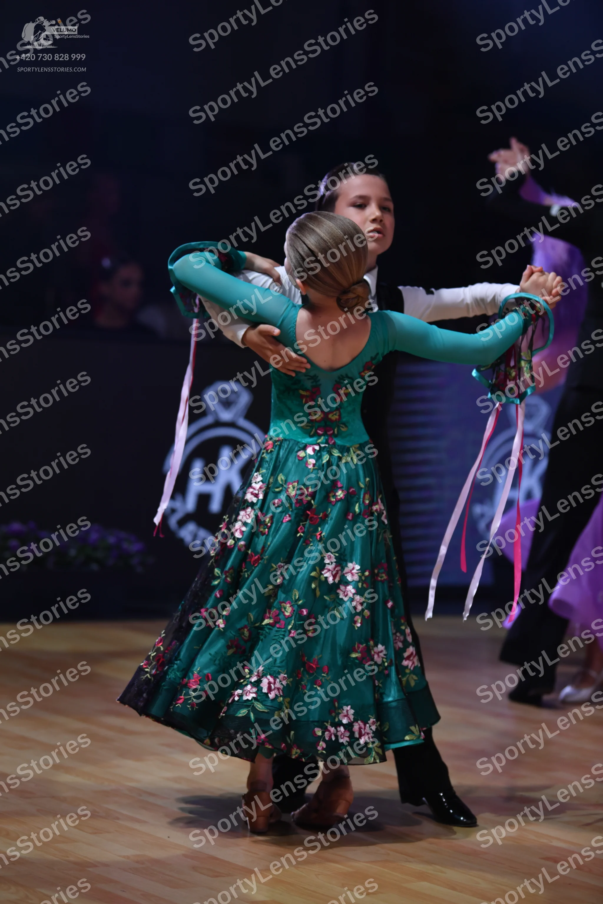 Dancesport competitor: Female dancer: teal long-sleeved dress with a pink and white floral pattern and