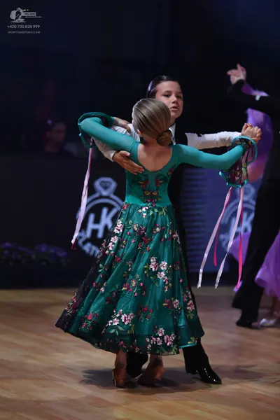 Dancesport competitor: Female dancer: teal long-sleeved dress with a pink and white floral pattern and 