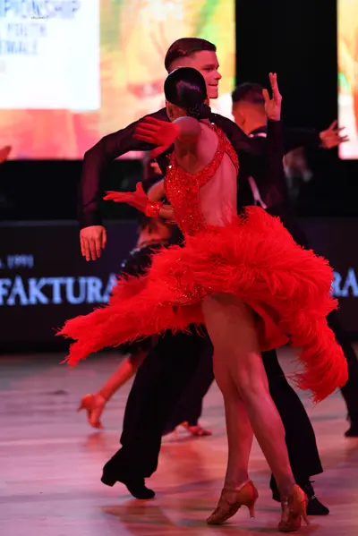 Dancesport competitor: Female dancer: red Latin dress with a large, feathered/fringed skirt and an embe