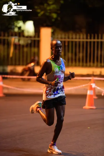 Marathon runner #222: Runner 1: multicolored tank top (white, blue, green, yellow), black shorts, whit