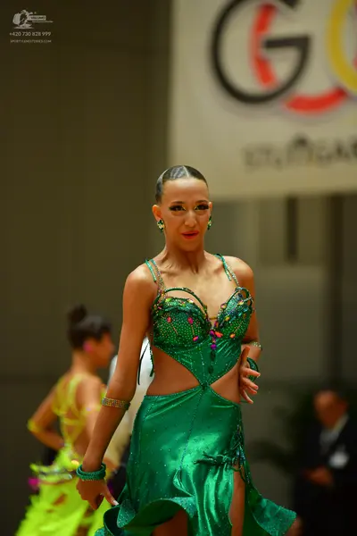 Dancesport competitor: Female dancer: green Latin dance dress with sequined bodice and thin straps