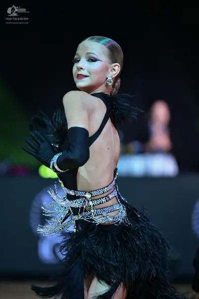 Dancesport competitor: Female dancer: black latin dance costume featuring a backless design, long black