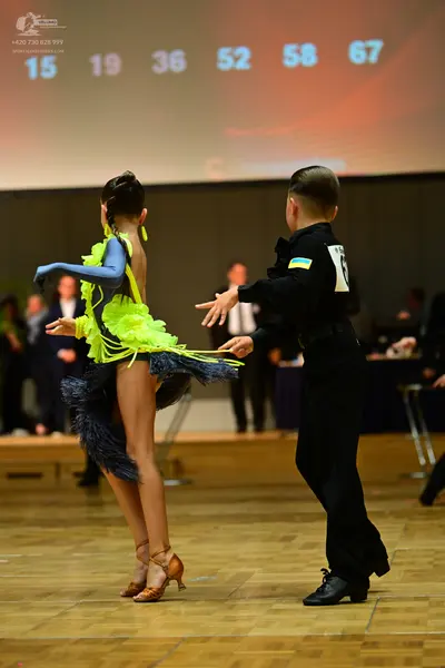 Dancesport competitor: Female dancer: lime green and black Latin dance dress with fringe and one long s