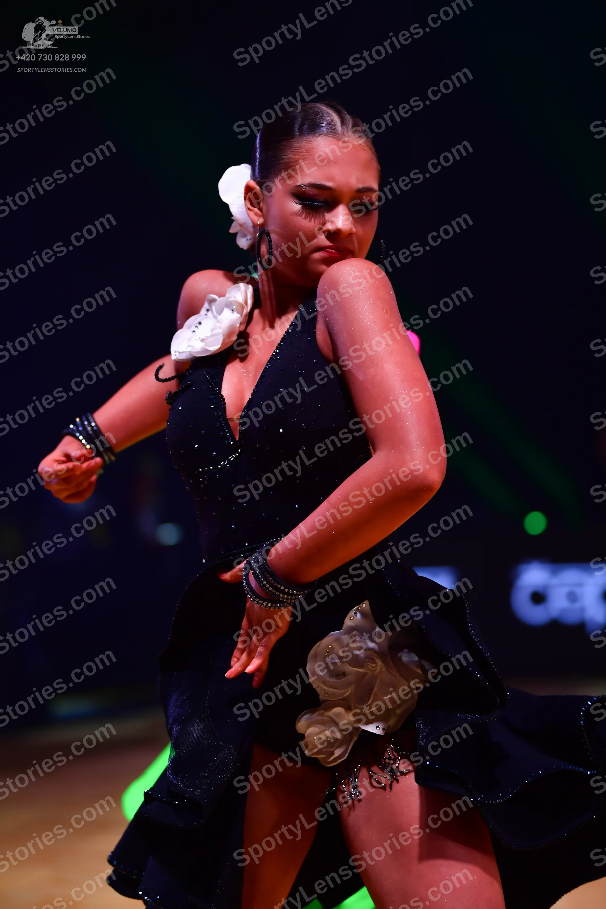 Dancesport competitor: Female dancer: black latin dress with subtle sparkles, featuring large white fab