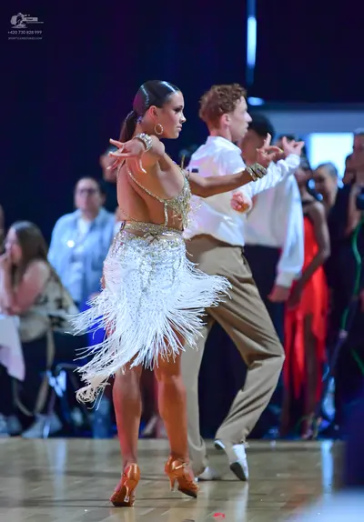 Dancesport competitor: Female dancer: silver/cream Latin dress with sequins and long fringe, wearing la
