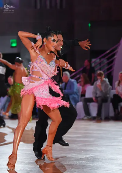 Dancesport competitor: Female dancer: light pink sequined Latin dress with a long pink feather-like fri