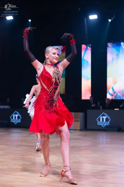 Dancesport competitor: Female dancer in foreground: red latin dress with a sequined bodice and a ruffle