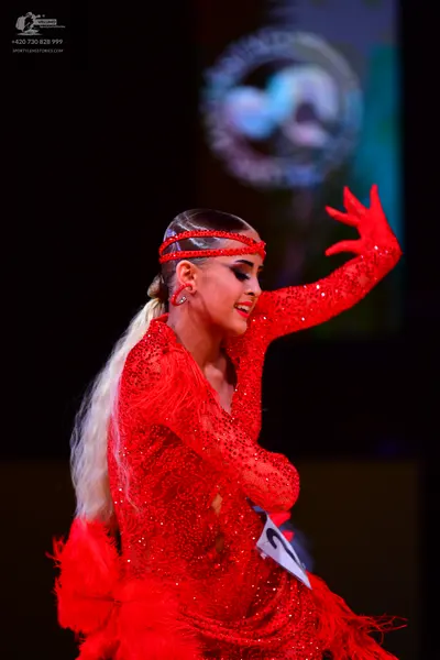 Dancesport competitor: Female dancer: red sequin Latin dress with long sleeves and a matching red headb