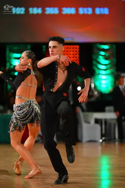 Dancesport competitor: Male dancer: black long-sleeved shirt, open at the chest, and black trousers, we