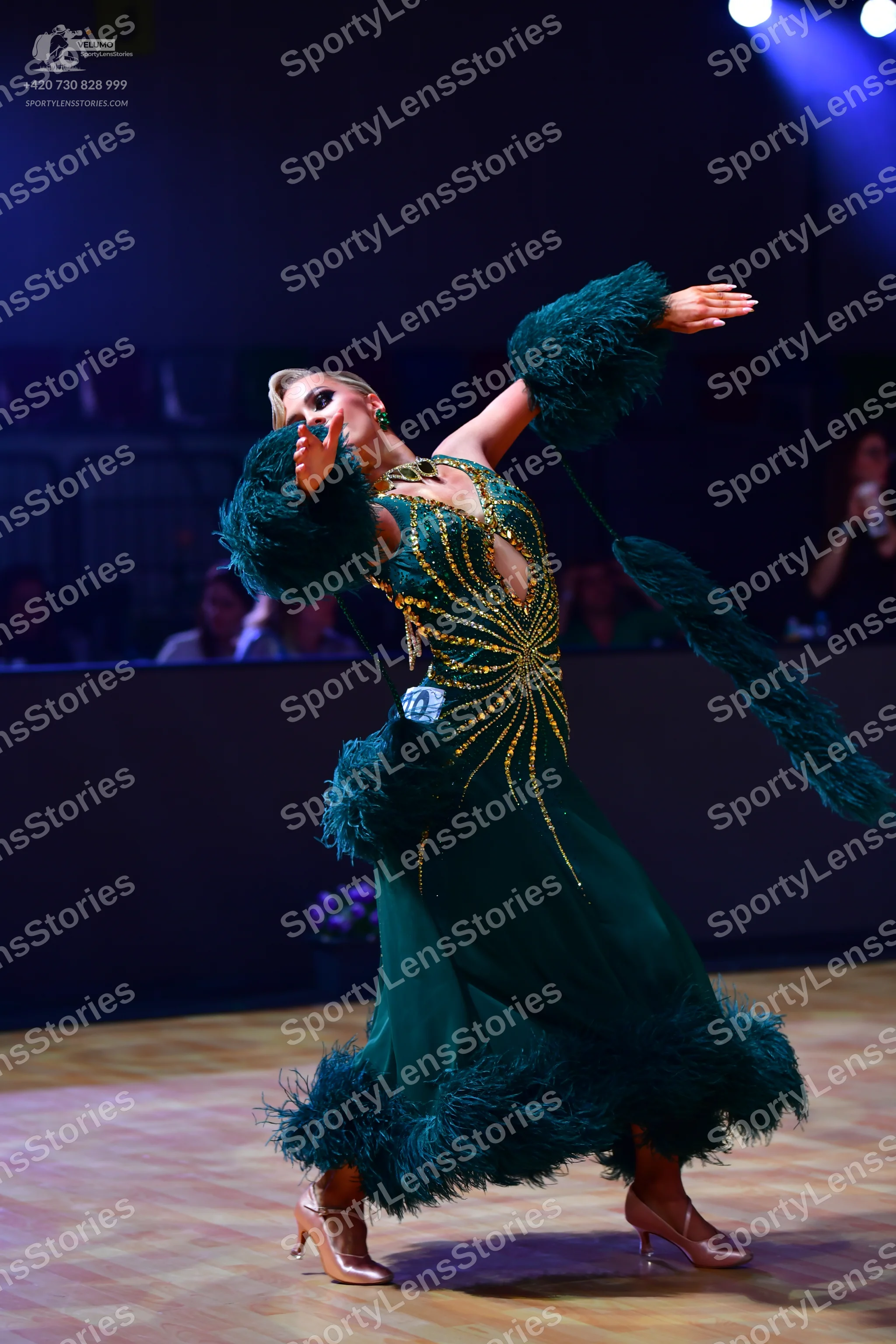 Dancesport competitor: Female dancer: emerald green ballgown with a gold sequin sunburst pattern on the