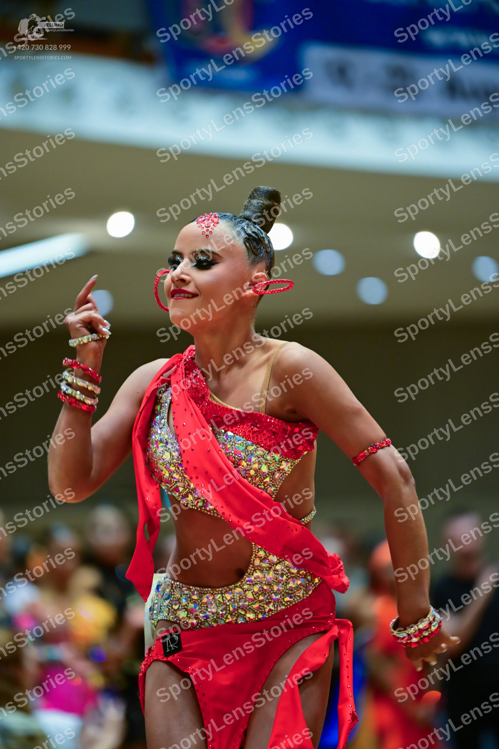 Dancesport competitor: Female dancer: red latin dress with gold and silver sequins, featuring an asymme