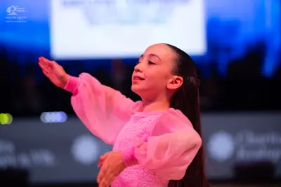 Dancesport competitor: Female dancer: pink long-sleeved dress with sheer sleeves and a textured bodice