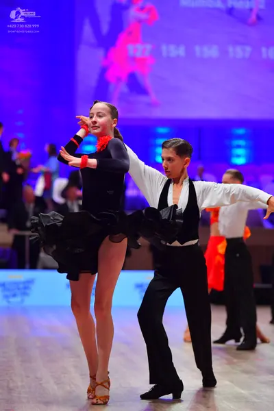 Dancesport competitor: Female dancer: black long-sleeved Latin dance top and a voluminous, ruffled blac