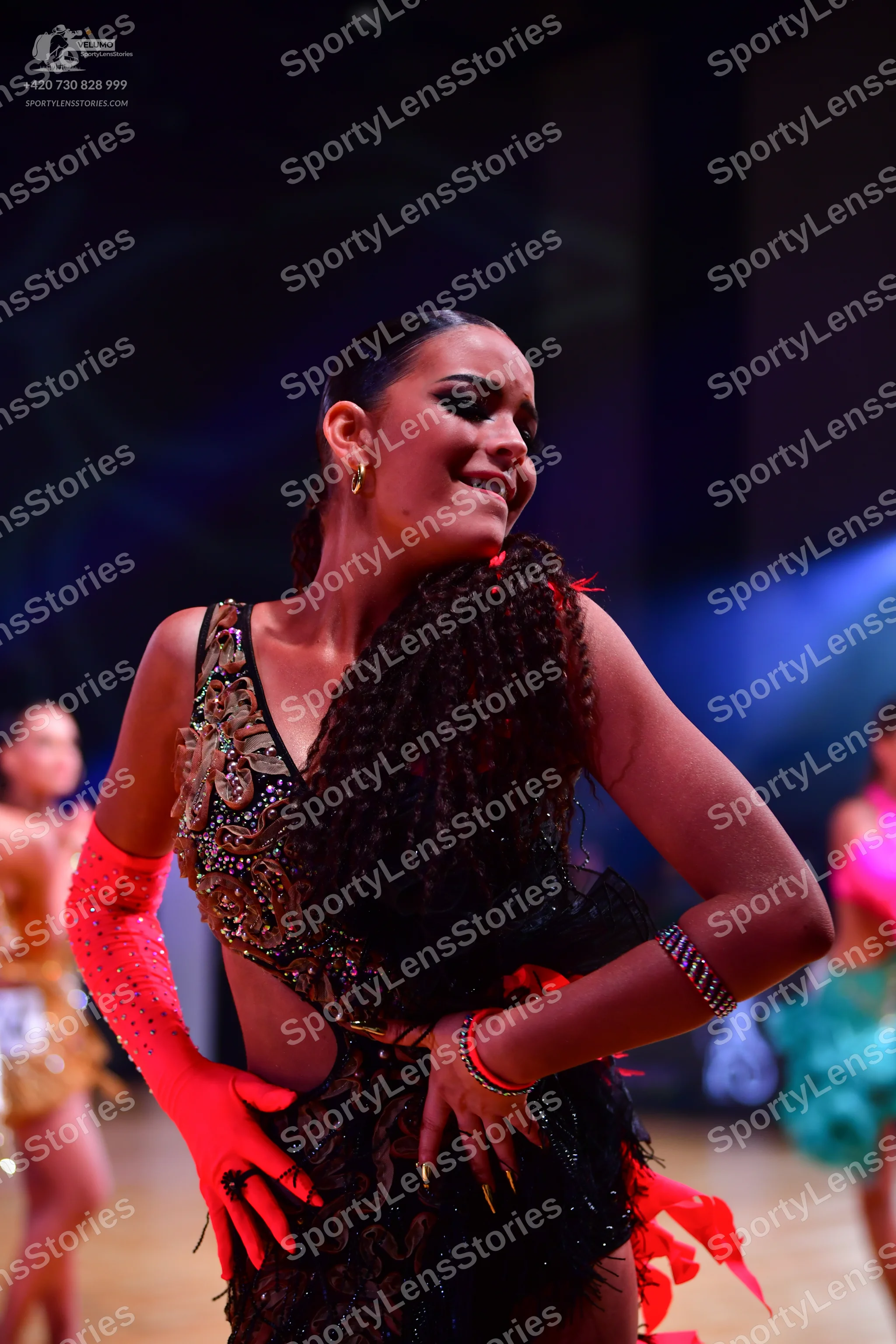 Dancesport competitor: Female dancer (foreground): black Latin dance dress with intricate gold and bron