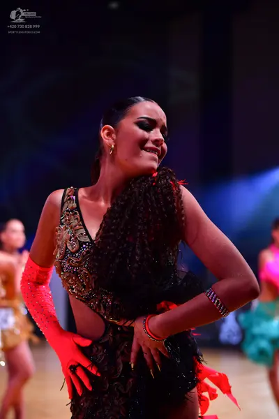 Dancesport competitor: Female dancer (foreground): black Latin dance dress with intricate gold and bron
