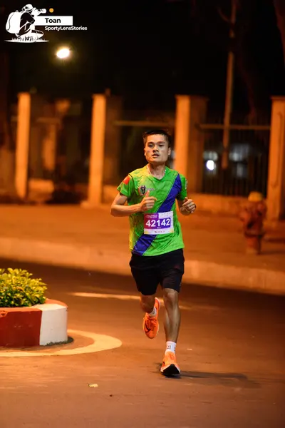 Marathon runner #42142: Runner 1: green and blue patterned jersey, black shorts, orange shoes