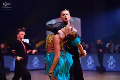 Dancesport competitor: Female dancer: turquoise blue Latin dance dress with long fringe and gold sequin