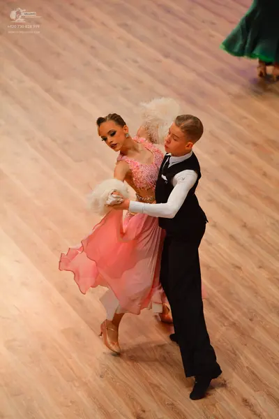 Dancesport competitor: Female dancer: pink ballgown with a lace or sequined bodice and a flowing skirt,