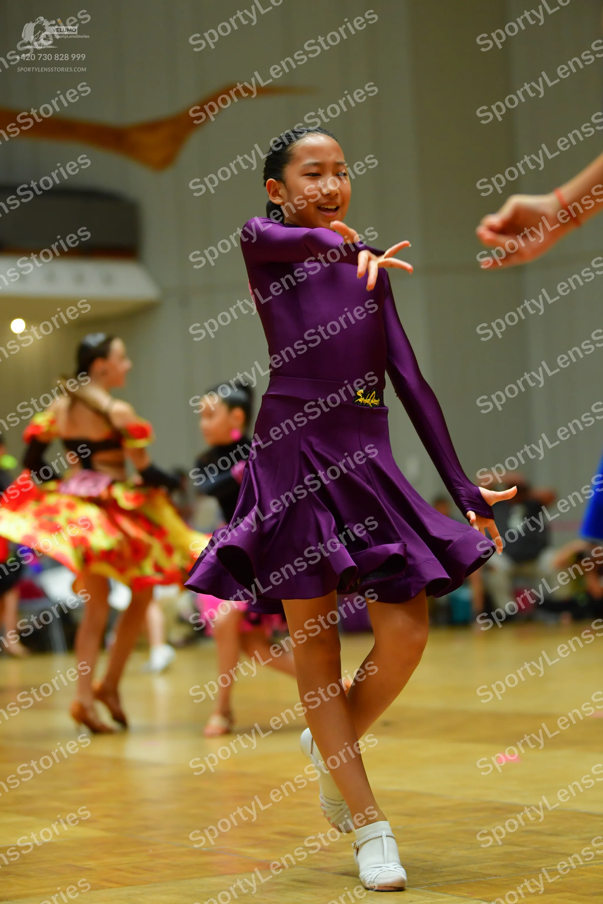 Dancesport competitor: Main dancer: purple, long-sleeved latin dress with a flared, ruffled skirt and s