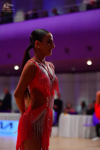 Dancesport competitor: Female dancer: red Latin dress with fringe and rhinestone embellishments
