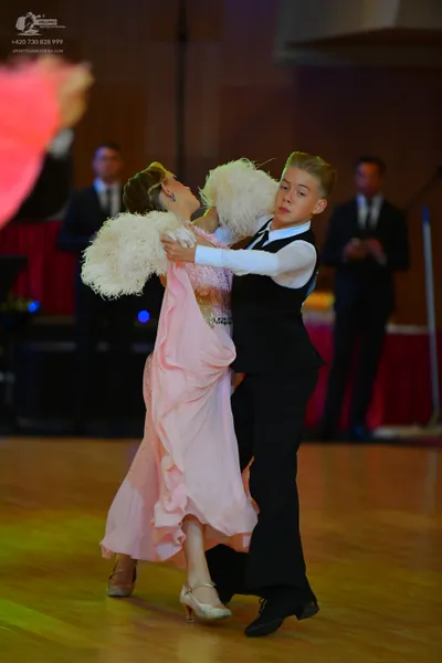 Dancesport competitor: Female dancer: light pink ballgown with a lace bodice and large white feather ac