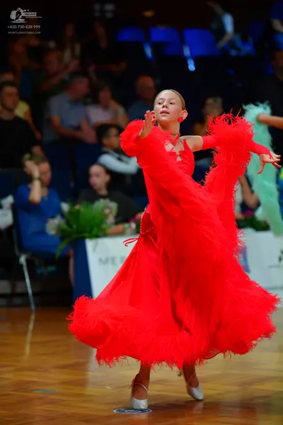 Dancesport competitor: Female dancer: bright red long-sleeved latin dance dress with voluminous, textur