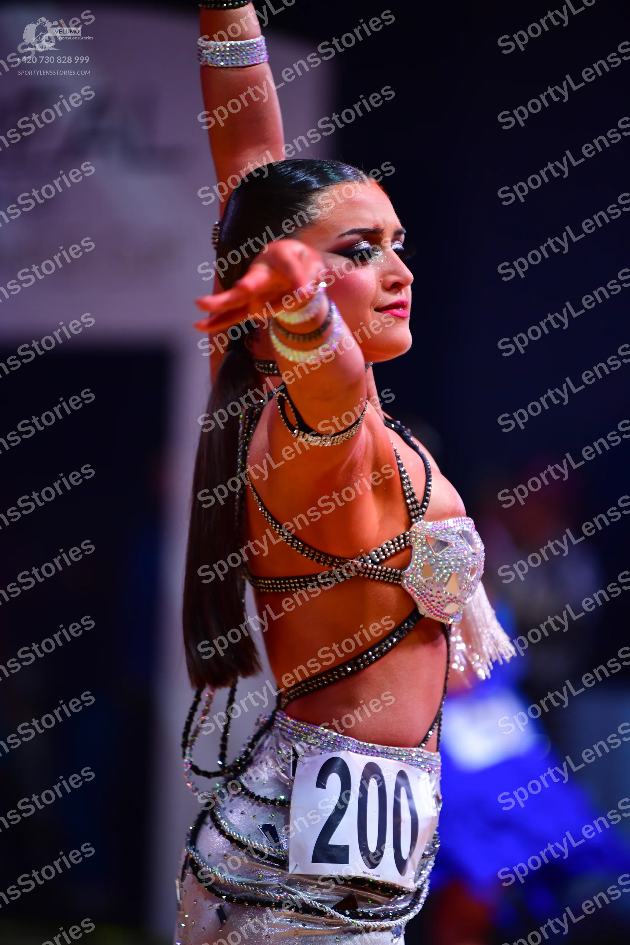 Dancesport competitor: Female dancer: silver/white Latin costume featuring many thin, sparkling, sequin
