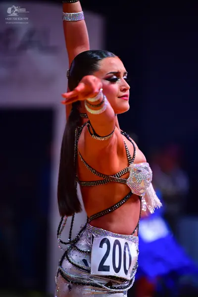 Dancesport competitor: Female dancer: silver/white Latin costume featuring many thin, sparkling, sequin
