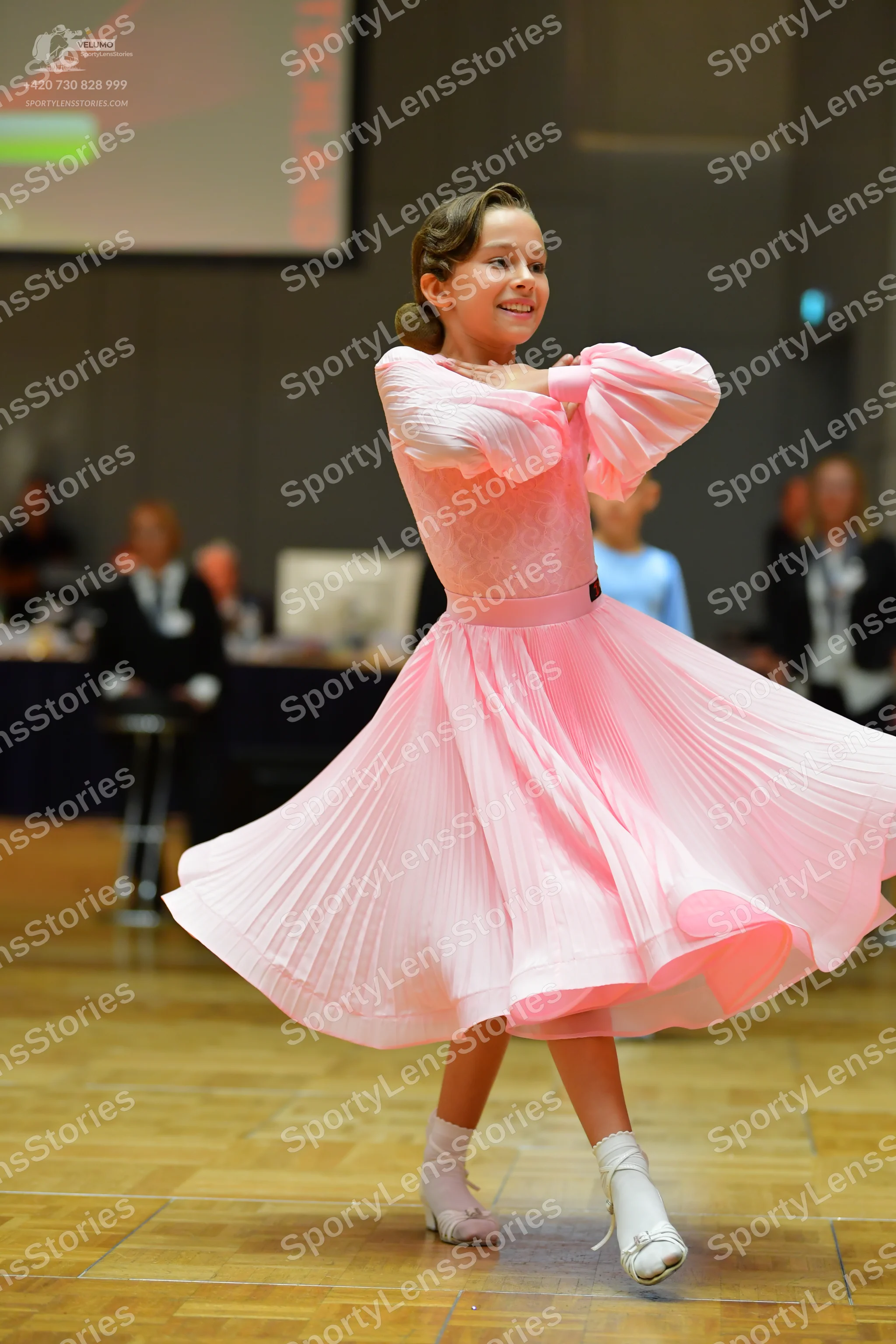 Dancesport competitor: Female dancer: light pink ballroom dress with long puffy sleeves and a full, ple