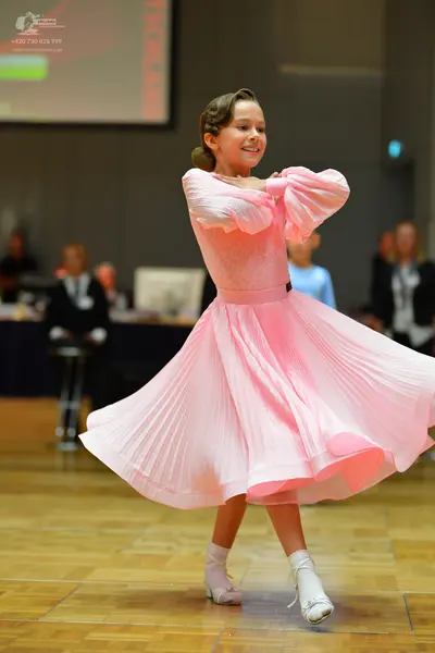 Dancesport competitor: Female dancer: light pink ballroom dress with long puffy sleeves and a full, ple