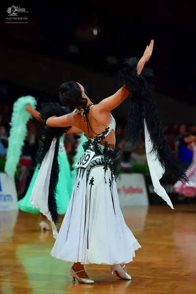 Dancesport competitor: Female dancer in foreground: white ballgown with black lace/sequin details and b