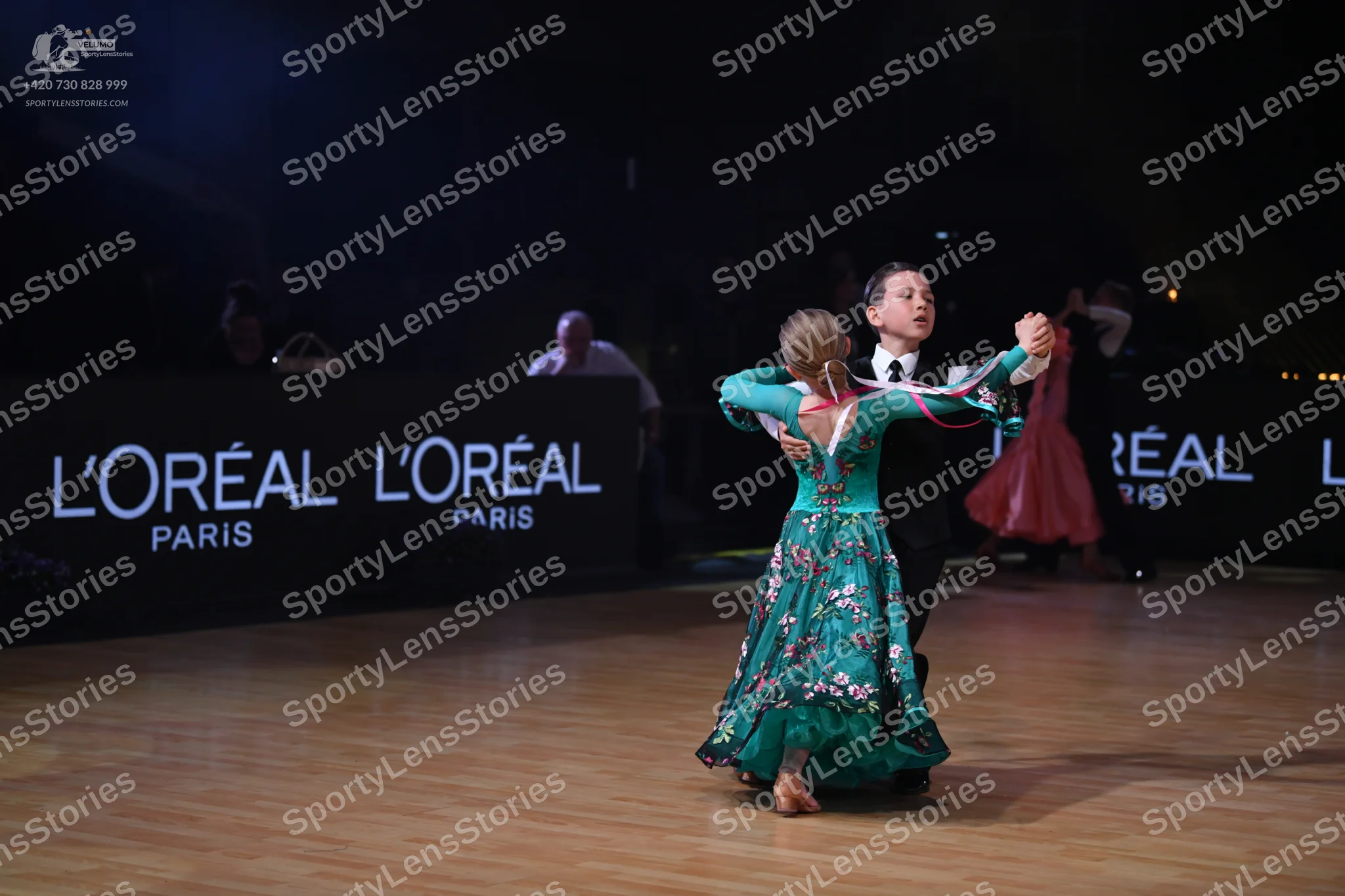 Dancesport competitor: Female dancer: teal ballgown with a floral pattern and long sleeves
