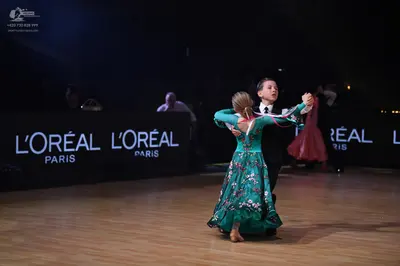 Dancesport competitor: Female dancer: teal ballgown with a floral pattern and long sleeves