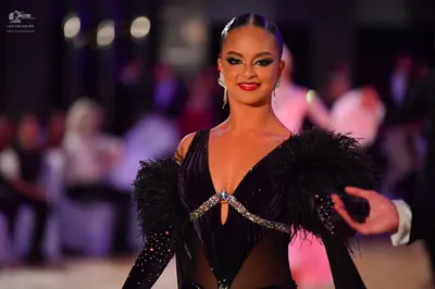 Dancesport competitor: Female dancer: black latin dress with sheer panels, silver/sparkly trim, and lar
