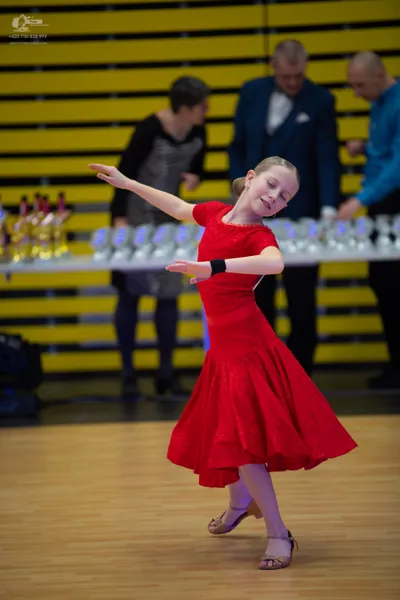 Dancesport competitor: ** Female: Red Latin Dress - The dress is a full, flowing Latin dress made of wh