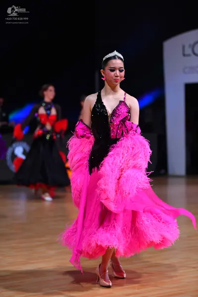 Dancesport competitor: Female dancer in foreground: black sequined latin-style bodice with a voluminous
