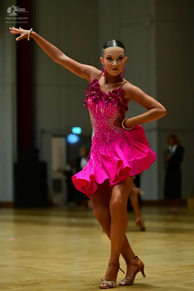 Dancesport competitor: Female dancer: bright pink latin dance dress covered in sequins with a ruffled n