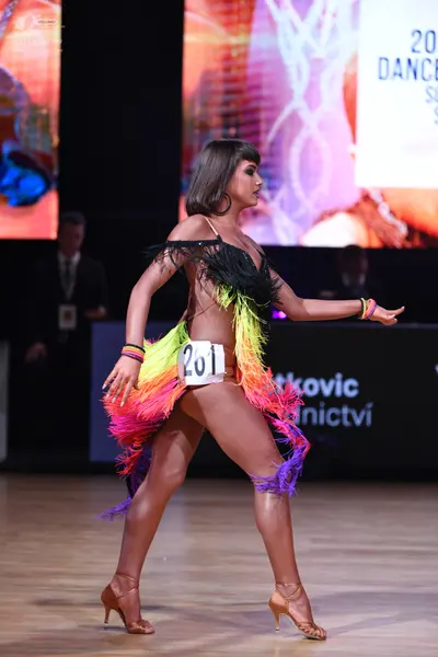 Dancesport competitor: Female dancer: multi-colored Latin dress with black, yellow, orange, pink, and p