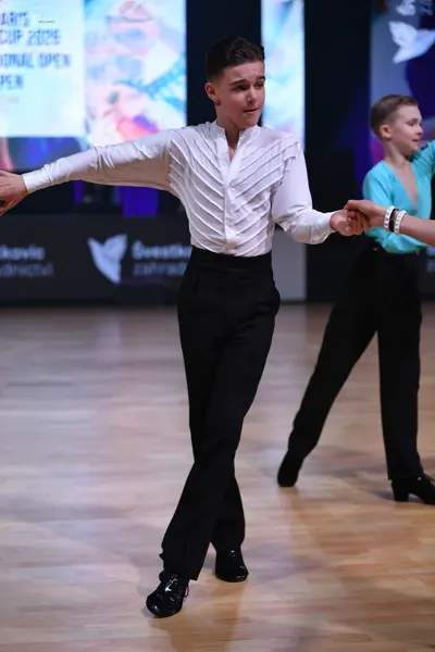Dancesport competitor: Male dancer: white long-sleeved shirt with a textured, pleated pattern, black tr