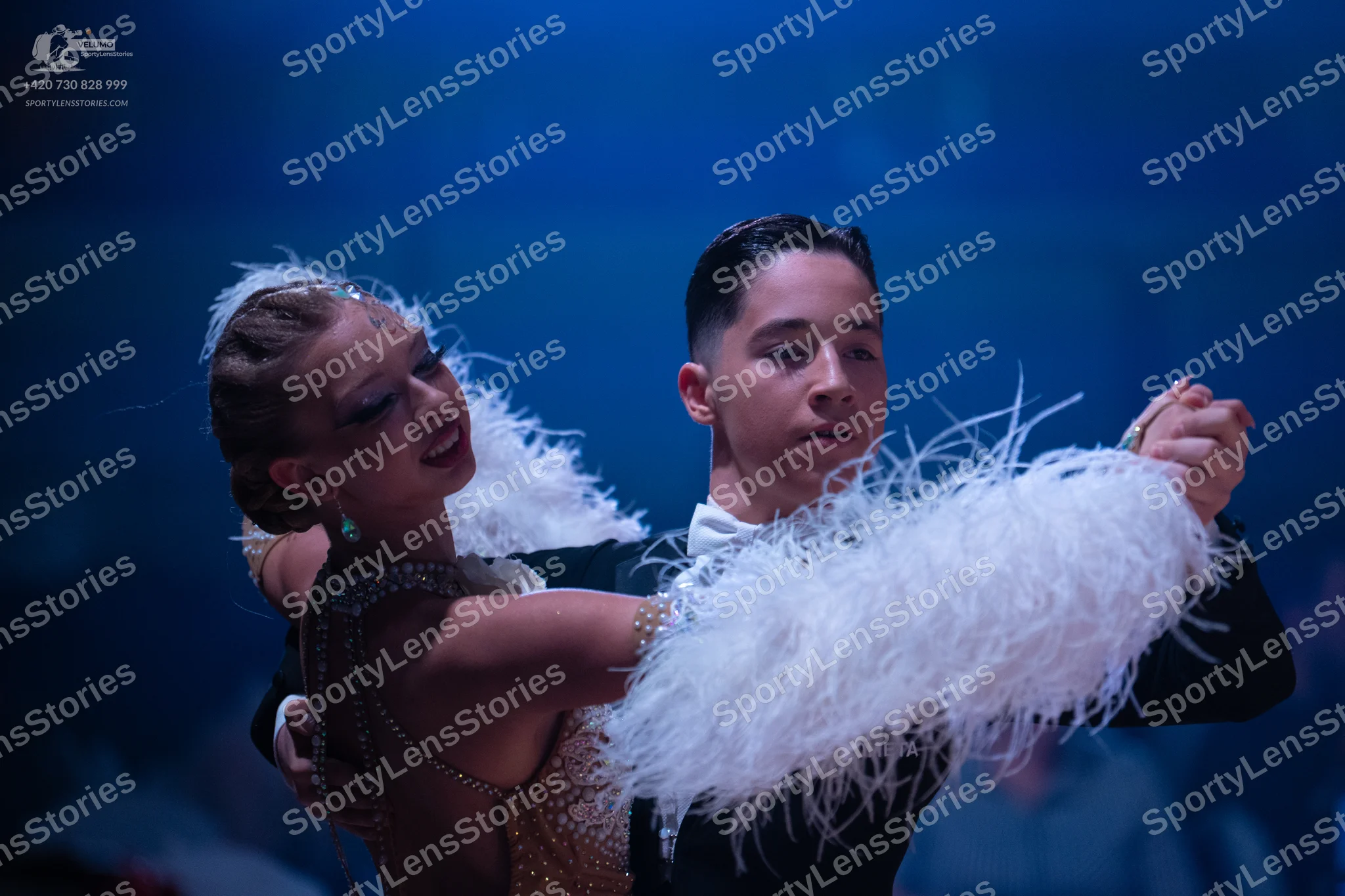 Dancesport competitor: Female dancer: champagne-colored sequined dress with large white feather accents