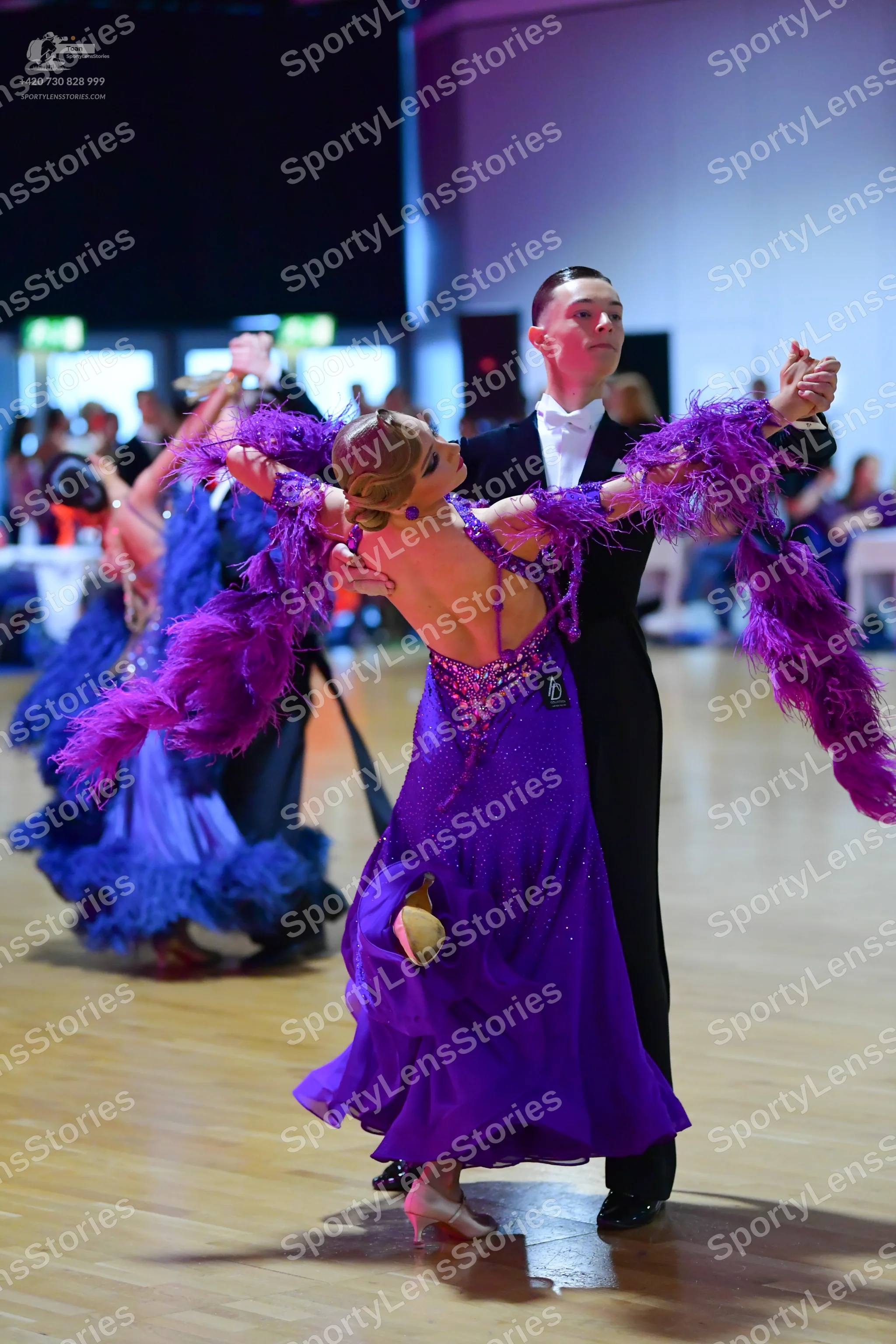 Dancesport competitor: Female dancer: purple ballgown with large purple feather/marabou trim on the arm