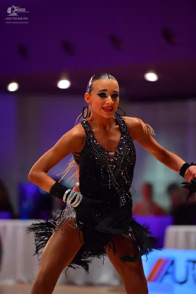 Dancesport competitor: Female dancer: black Latin dance dress with sequins and black fringe, and black 