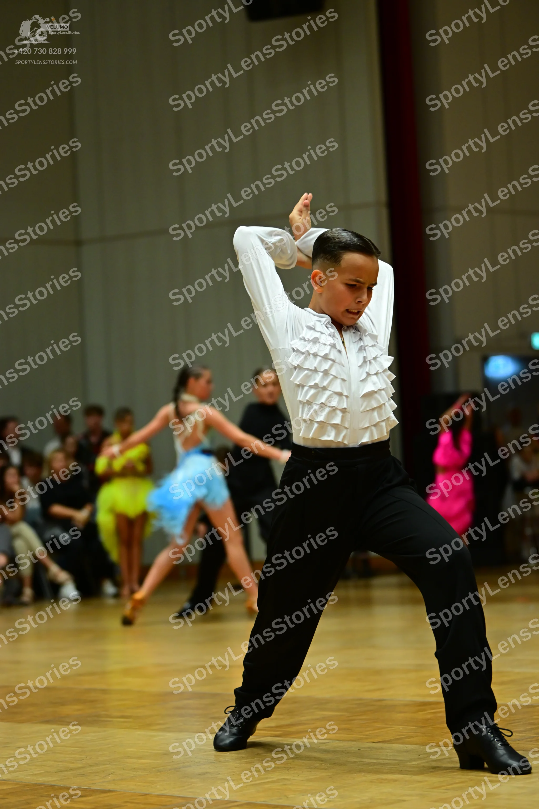 Dancesport competitor: Male dancer: white long-sleeved shirt with ruffles on the front, black trousers,