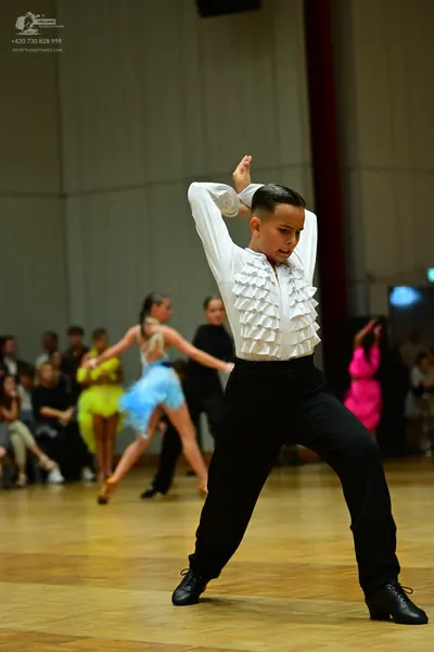 Dancesport competitor: Male dancer: white long-sleeved shirt with ruffles on the front, black trousers,