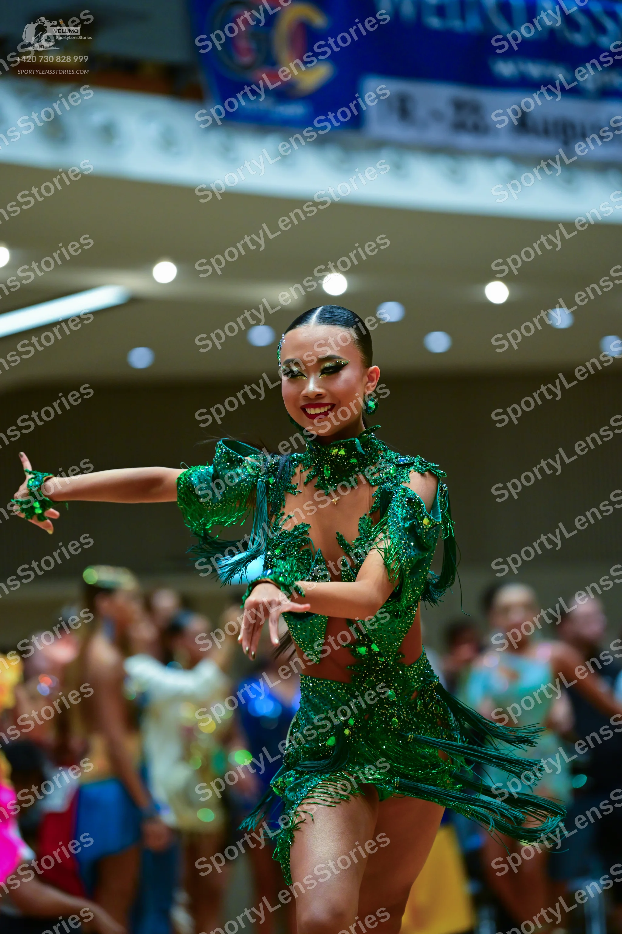 Dancesport competitor: Female dancer in foreground: green latin dance dress with green sequins, green f