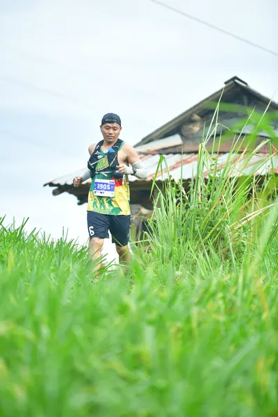 Marathon runner #7055: Runner 1: dark tank top with patterns, dark shorts, and a dark cap