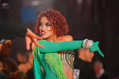 Dancesport competitor: Female dancer: green Latin dance dress with long sleeves, green fringe, and silv