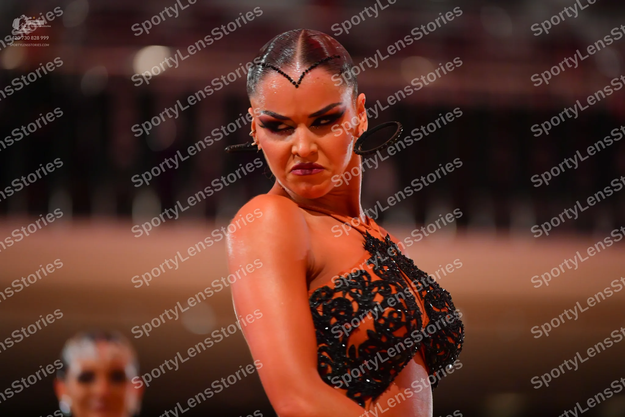 Dancesport competitor: Female dancer: black Latin dance costume with an intricate lace or sequin patter