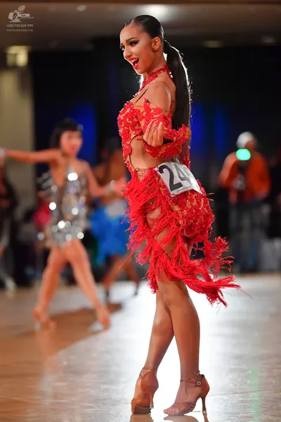 Dancesport competitor #24: Female dancer in foreground: red Latin dress with fringe and cutouts