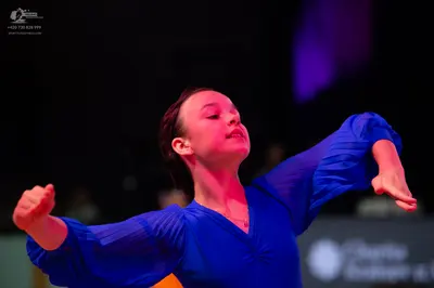 Dancesport competitor: Female dancer: blue latin dress with long, sheer, textured sleeves